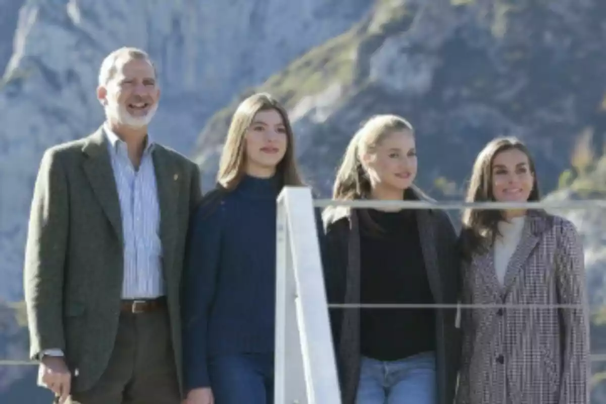 Cuatro personas -que son la Familia Real Española- posan juntas al aire libre con montañas de fondo en un día soleado en Asturias.