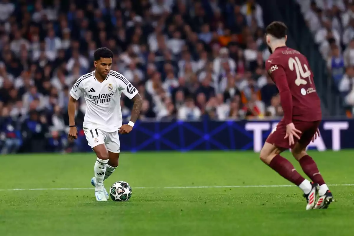 A player in a white uniform controls the ball as an opponent in a brown uniform approaches in a stadium full of spectators. A player in a white uniform controls the ball as an opponent in a brown uniform approaches in a stadium full of spectators.